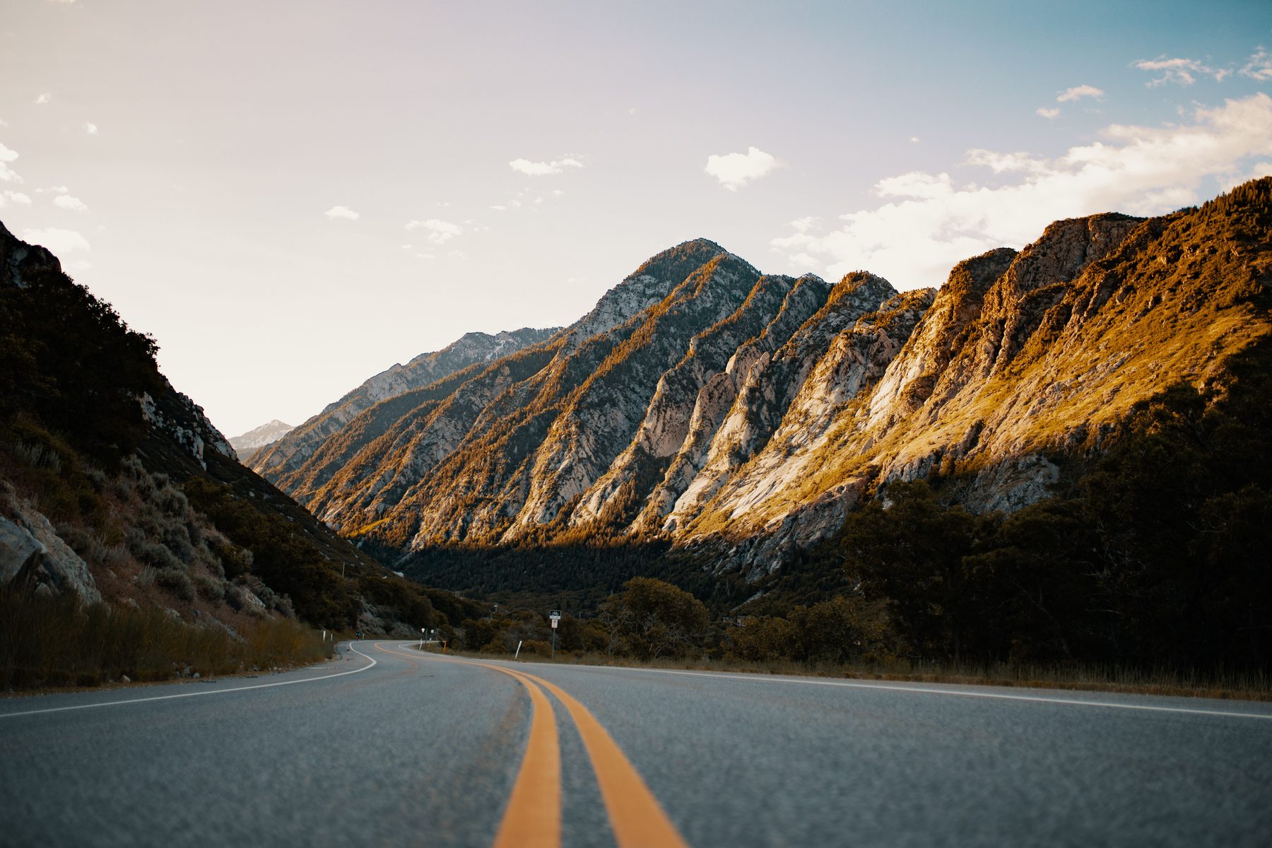 A mountain road winding into a canyon at golden hour